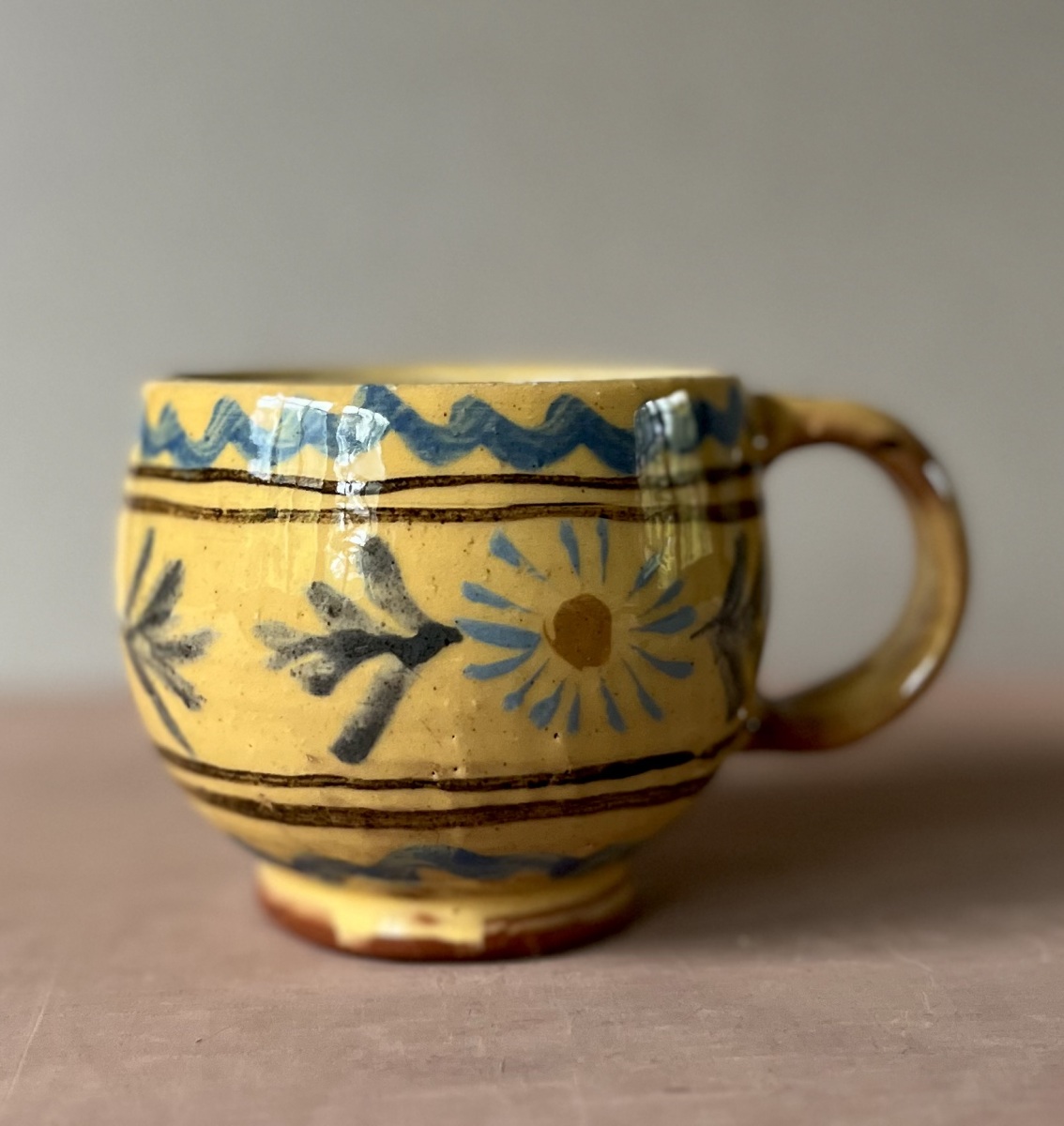 Yellow rounded coffee cup with blue daisy